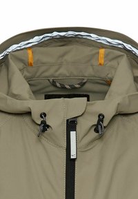 Veste à capuche kaki avec fermeture éclair noire, cordons ajustables sur la capuche et surpiqûres orange à l’intérieur du col.