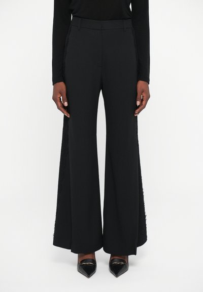 Pantalones de pierna ancha negros, confeccionados en una tela suave, con paneles de encaje en los lados. El diseño incluye una cinturilla ajustada y tacones altos.
