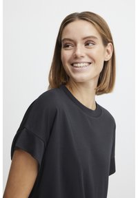 Svart kortärmad t-shirt med rund halsringning, avslappnad passform och mjuk textur. Den har rullade ärmslut och släta sömmar.