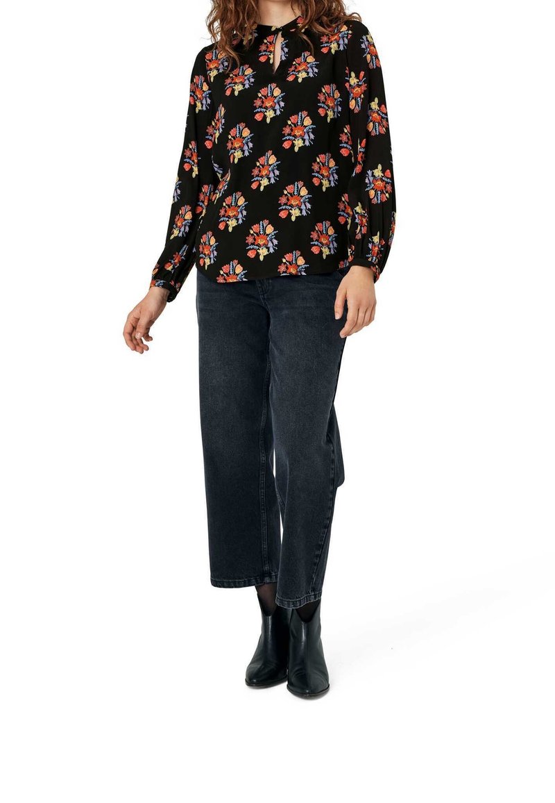 Long-sleeve black blouse with colorful floral pattern paired with high-waisted dark denim jeans and black ankle boots.