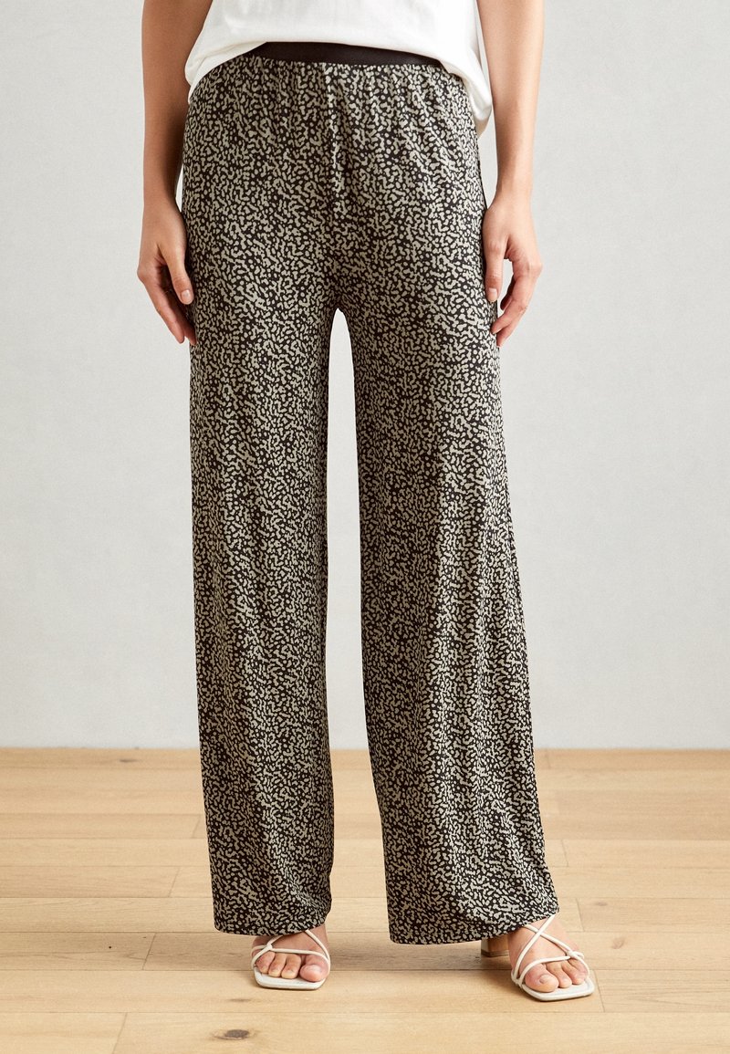 Pantalons à jambes larges en tissu léger, avec un motif abstrait noir et crème, une taille élastique et une coupe décontractée.
