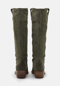 Botas de ante verde hasta la rodilla con un diseño ligeramente holgado, que cuentan con un tacón de madera apilada y lengüetas en la parte superior para facilitar el uso.