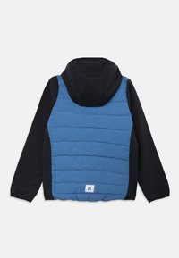 Blå quiltet vest med svart hette og ermer, med horisontale sting og en logotagg nederst til høyre. Vanntett materiale.