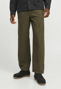 Pantalones de pierna ancha verde oliva hechos de una tela duradera, con bolsillos clásicos y una textura suave, combinados con zapatos negros y una camiseta negra.