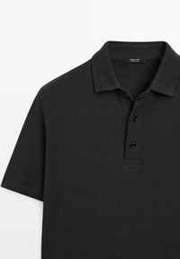 Černé polo tričko vyrobené z texturované tkaniny, s klasickým límcem a zapínáním na tři knoflíky. Krátké rukávy s čistými okraji.