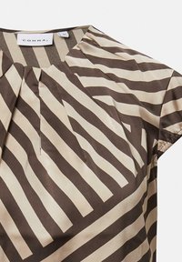 Kurzärmlige Bluse mit braunen und beigefarbenen diagonalen Streifen und einem runden Ausschnitt mit dezenten Fältchen am Kragen.