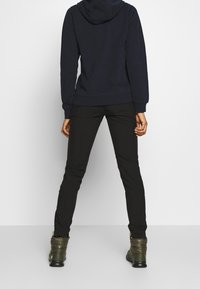 Marinblå sweatshirt med huva, svarta åtsittande byxor och gröna isolerade stövlar. Klädseln har en avslappnad design och mjuka texturer.