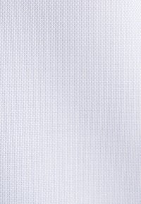 Gros plan sur un tissu blanc avec un motif de tissage en grille petite et régulièrement espacée, créant une surface texturée.