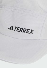 Hvit caps laget av teksturert stoff med vertikale striper. Har den svarte "TERREX" logoen foran og en buet skjerm.