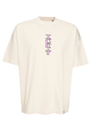 Maglietta oversize color crema in cotone. Presenta un design grafico verticale viola al centro davanti e maniche corte.