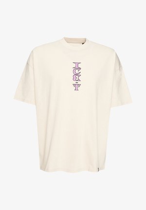 Maglietta oversize color crema in cotone. Presenta un design grafico verticale viola al centro davanti e maniche corte.