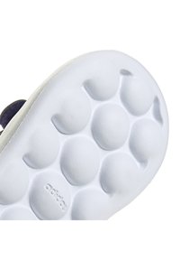 Suela de zapato de goma blanca con patrones texturizados circulares y la marca "adidas". El acabado suave y los bordes redondeados resaltan el diseño.