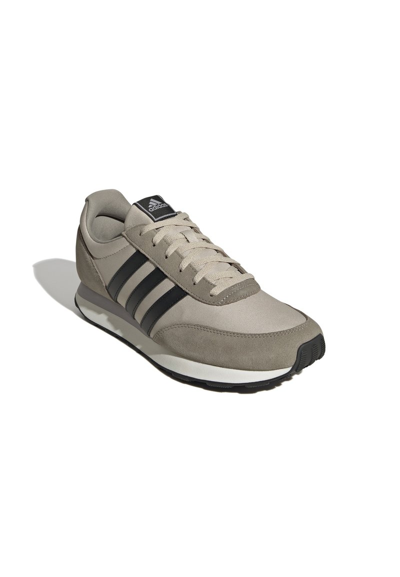 Lichtgrijze sneaker van suede en mesh materialen. Heeft drie zwarte strepen, een witte tussenzool en een ronde neusdesign.
