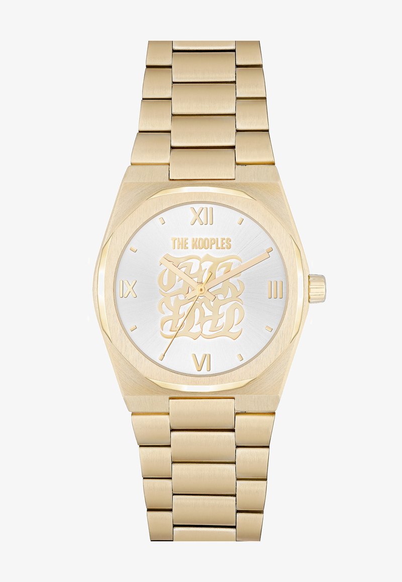 Złoty zegarek z srebrną tarczą, ośmiokątną kopertą i bransoletą w kształcie ogniwa. Posiada złote wskazówki, numeryczne znaczniki godzin oraz logo marki.