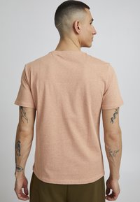 Tricou cu mânecă scurtă, guler rotund, dintr-un amestec de bumbac ușor piersică, cu o textură subtilă. Prezintă un tiv rotunjit și un design confortabil.
