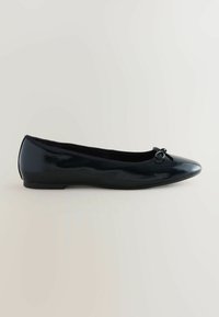 Ballerines en cuir verni noir avec un bout arrondi, un petit nœud à l'avant et une semelle plate. Texture lisse et design épuré.