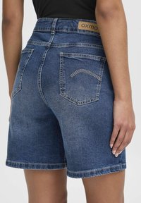 Denimshorts i mörkblått med hög midja. Har fem fickor, kontrasterande s�ömmar och en märkesläderlapp på baksidan.