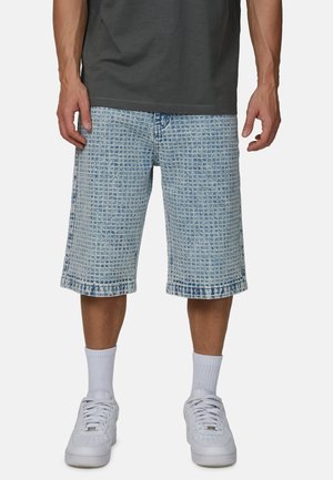 Szorty dżinsowe w jasnoniebieskim kolorze z teksturowanym wzorem kratki, o prostym kroju i postrzępionych brzegach. Połączone z białymi trampkami i skarpetkami.