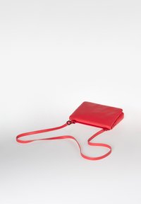 Borsa a tracolla rossa in pelle con una superficie liscia, forma rettangolare slim e tracolla regolabile. Presenta un logo discreto sulla superficie.