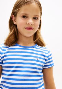 Κοντομάνικη μπλούζα με μπλε και λευκές ρίγες και ριμπ υφή, με μικρό λογότυπο και κυματιστές άκρες στα μανίκια.