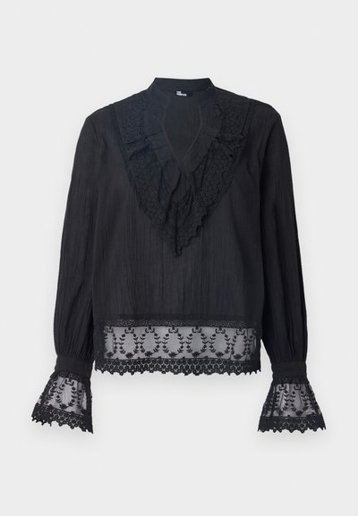 Bluză neagră din material texturat, cu un guler volanat și accente din dantelă transparentă la mâneci și la marginea de jos, decorate cu broderie florală.
