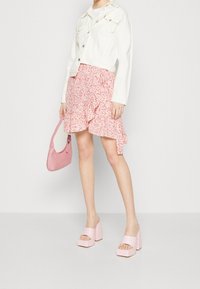 Chaqueta de denim blanca, falda rizada floral rosa, bolso rosa y tacones de plataforma gruesos rosas. Diseño limpio con una estética femenina.