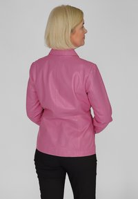 Roze leren jas met een getailleerd ontwerp, staande kraag en stiksel-details, getoond vanaf de achterkant naast zwarte broek.