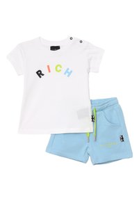 T-shirt bianca in cotone con testo "RICH" multicolore e due bottoni a pressione sulla spalla, abbinata a pantaloni corti in cotone blu con lacci verdi.