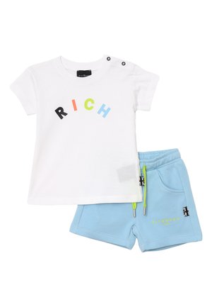 T-shirt bianca in cotone con testo "RICH" multicolore e due bottoni a pressione sulla spalla, abbinata a pantaloni corti in cotone blu con lacci verdi.