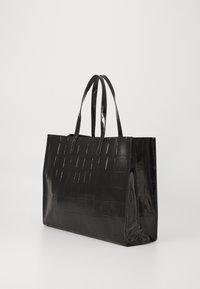 Saco tote preto brilhante com padrão de crocodilo em relevo, duas alças de ombro e uma forma retangular estruturada sobre um fundo branco.