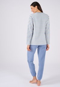 Maglia in pile leggera a strisce, di un blu soft e crema; abbinata a pantaloni in pile leggeri blu chiaro con polsini elasticizzati.
