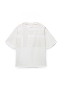 Crème kleurig t-shirt met korte mouwen en een textuurpatroon over de bovenrug en schouders. Ronde halslijn, ontspannen pasvorm.