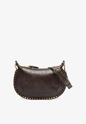 Bruine leren handtas met een gebogen vorm, met studs langs de onderrand en een verstelbare band. Accenten van goudkleurige hardware.