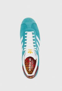 Baskets en daim turquoise avec des bandes blanches en cuir, une languette rembourrée et une semelle accentuée de rouge. Semelle intérieure multicolore à motifs avec le logo de la marque.