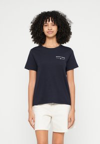 Tmavomodré bavlnené tričko s krátkymi rukávmi, okrúhlym výstrihom a bielym nápisom "GANT 1949" vytlačeným na hrudi.