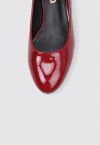 Escarpin rouge brillant avec un bout arrondi et une finition vernie lisse. La semelle intérieure est noire avec un détail de logo subtil.