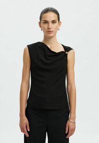 Top senza maniche nero con scollatura drappeggiata e dettaglio asimmetrico sulla spalla fissato da un accessorio. Tessuto morbido con un design aderente.