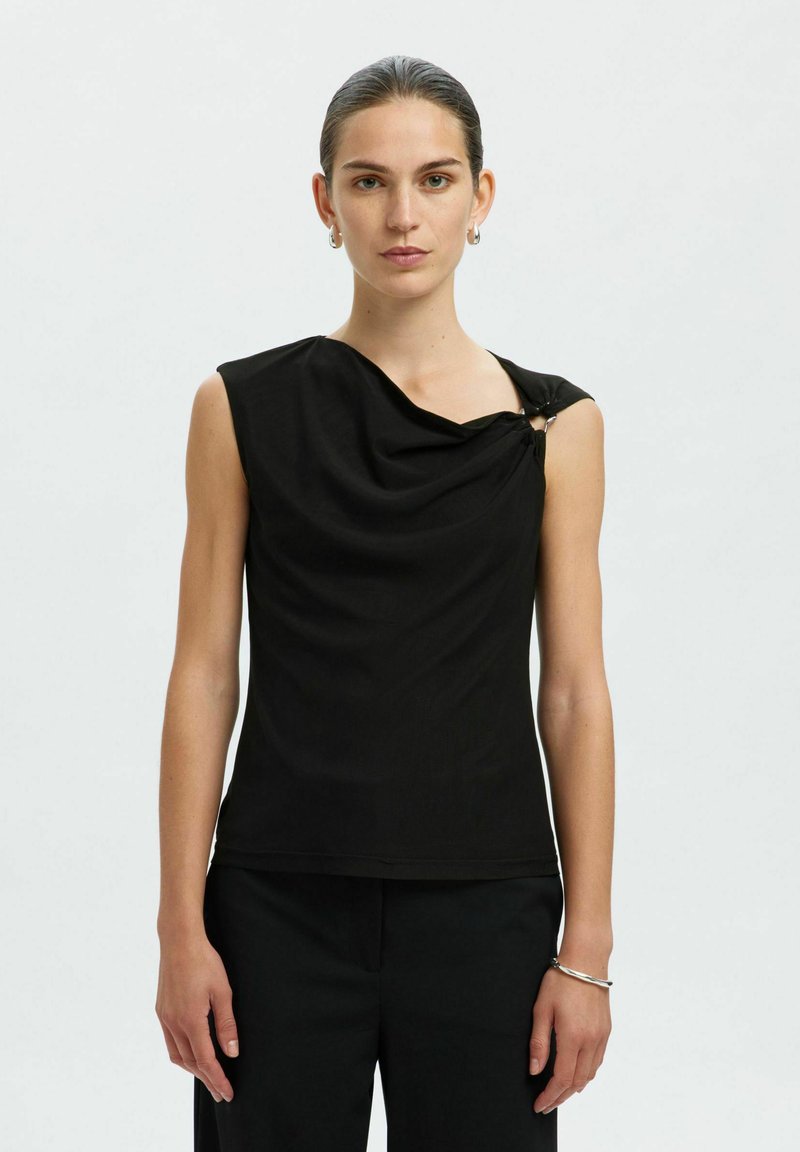 Top senza maniche nero con scollatura drappeggiata e dettaglio asimmetrico sulla spalla fissato da un accessorio. Tessuto morbido con un design aderente.