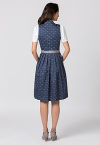 Navy blue dress with a fitted bodice and pleated skirt. Features a floral pattern, silver belt, and a white blouse underneath.