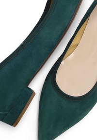 Bailarinas de ante en color verde azulado con punta afilada, borde elástico en la apertura y un tacón bajo cuadrado con suela de goma natural.