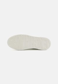 Suola di sneaker bianca con pattern di presa testurizzato e logo sollevato che legge "EXCHANGE". Bordi lisci e design della punta leggermente arrotondato.