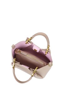 Vista dall'alto di una borsa a mano realizzata in pelle crema con un interno rosa, hardware dorato, doppi manici e un compartimento con zip.