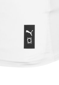 Biała koszulka sportowa z czarną metką z logo przedstawiającą skaczącego pumę z zębami. Gładki materiał z przeszytymi krawędziami dla zwiększenia trwałości.