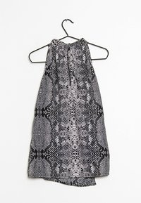 Haut dos nu à motif noir et blanc avec un design texturé en peau de serpent, doté d'un nœud au niveau du cou et d'un ourlet légèrement incurvé.