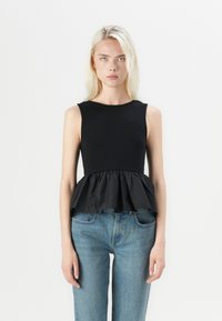 Musta peplum-top ribakujundusega ja ilma varrukateta, sujuva musta kangaga alumises osas, koos siniste teksadega.