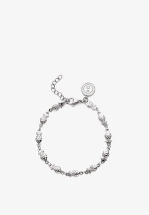 Pulsera de plata con charms con forma de pez enlazados y una placa redonda cerca del cierre de langosta, exhibida sobre un fondo blanco.