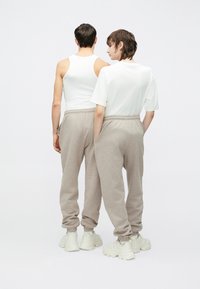 Δύο άτομα φορούν άνετο, ανοιχτό γκρι φόρμες με ελαστική μέση και μανσέτες, συνδυασμένες με λευκά tops και chunky λευκά αθλητικά παπούτσια.