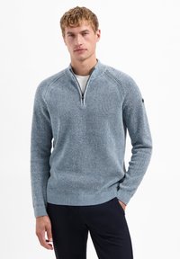 Lichtblauwe vest met rits en geribbelde textuur, voorzien van strakke manchetten. Heeft een rits tot een kwart lengte en raglanmouwen voor een moderne pasvorm.