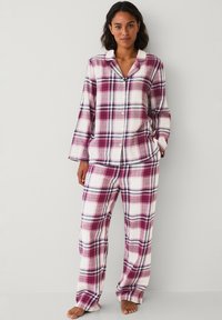 Geruite pyjama set in tinten van roze, wit en marineblauw, met een knoopsluiting bovenstuk met kraag en wijde broek. Zachte stoftextuur.