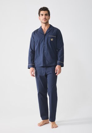 Navy cotton pajama set featuring a button-up shirt with a pocket and contrast piping, paired with matching straight-leg pants.